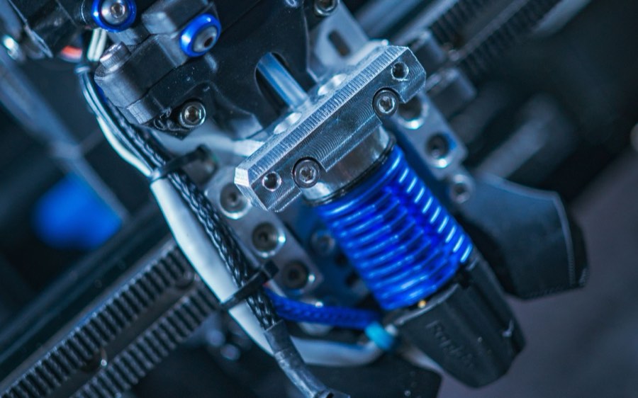 Close-up of a 3D printer extruder head under blue light