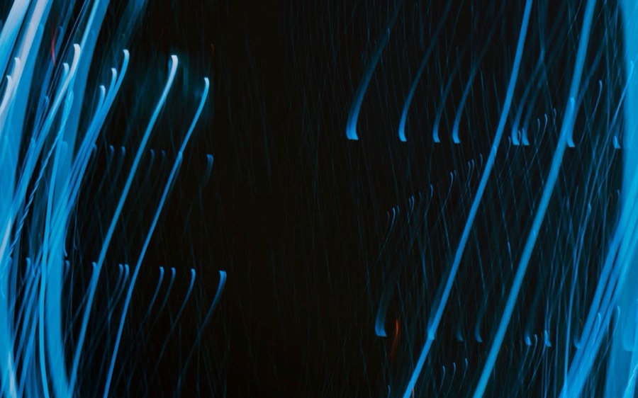 Long exposure photograph of blue light trails against black